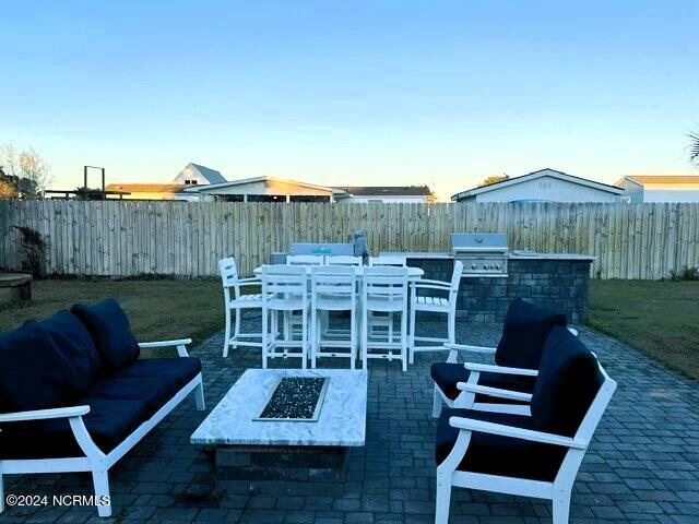 view of patio with area for grilling, exterior kitchen, and an outdoor living space with a fire pit