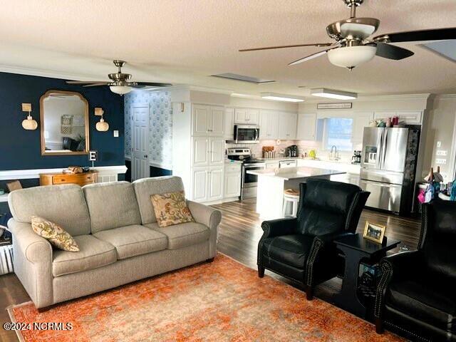 living room with ornamental molding, a textured ceiling, and light hardwood / wood-style flooring