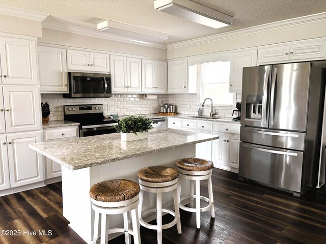 117 Buds Ln, Cedar Point, NC 28584 - kitchen featuring stainless steel appliances, ornamental molding, white cabinets, a textured ceiling, and a kitchen breakfast bar