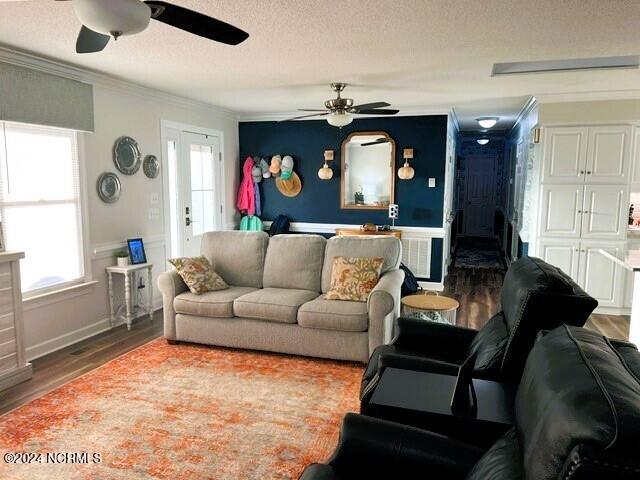 living room with french doors, crown molding, a textured ceiling, a healthy amount of sunlight, and wood-type flooring