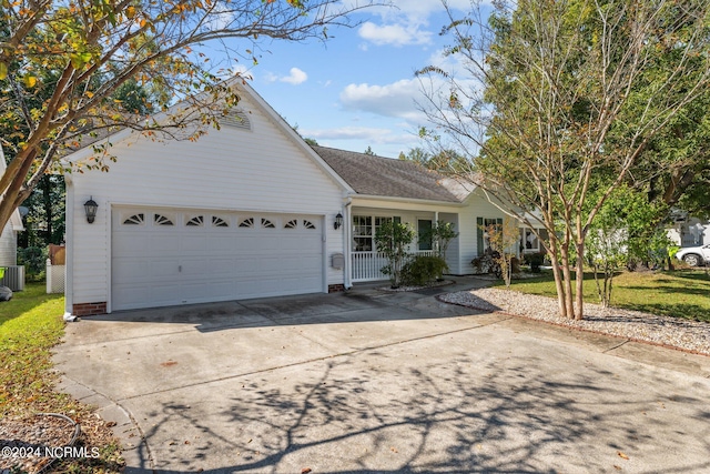 view of front of home with covered porch, a garage, and central AC unit