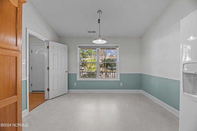 empty room featuring a textured ceiling and vaulted ceiling