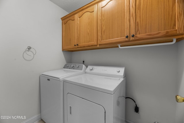 laundry area featuring a textured ceiling, separate washer and dryer, and cabinets