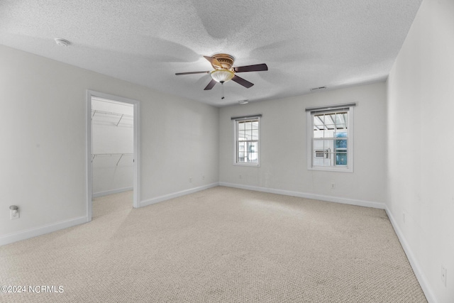 empty room with light carpet, a textured ceiling, and ceiling fan