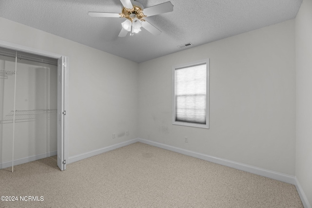 unfurnished bedroom featuring light carpet, a closet, a textured ceiling, and ceiling fan