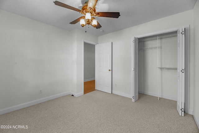 unfurnished bedroom featuring a textured ceiling, light colored carpet, a closet, and ceiling fan