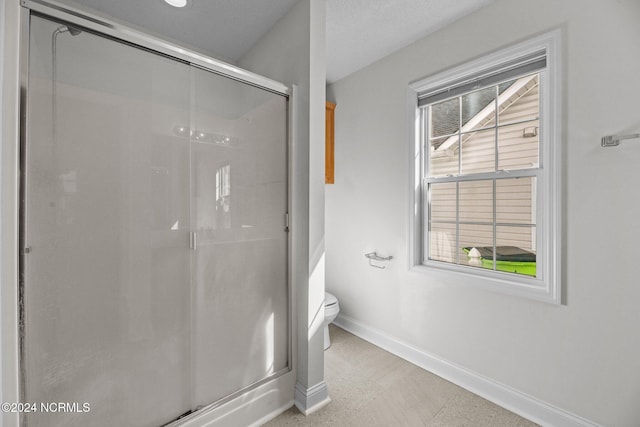 bathroom featuring a textured ceiling, toilet, and walk in shower