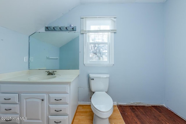 bathroom with toilet, vaulted ceiling, wood-type flooring, and vanity