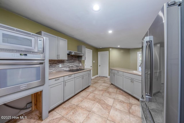 kitchen with backsplash, appliances with stainless steel finishes, light tile patterned flooring, and wall chimney exhaust hood