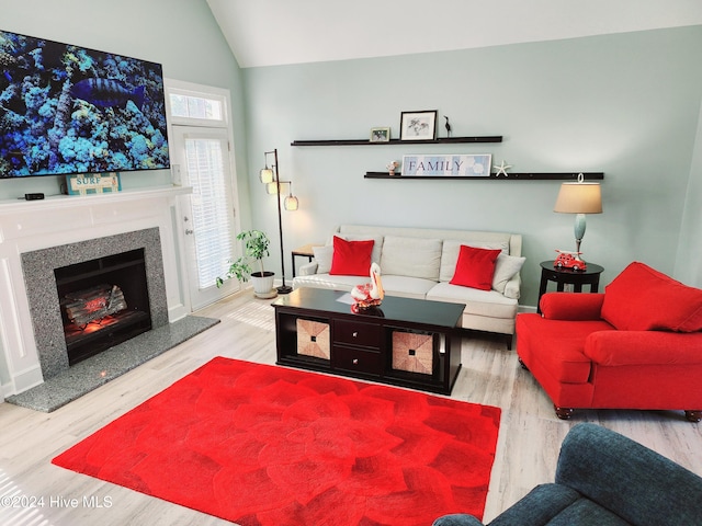 living room with lofted ceiling, a fireplace, and light hardwood / wood-style floors