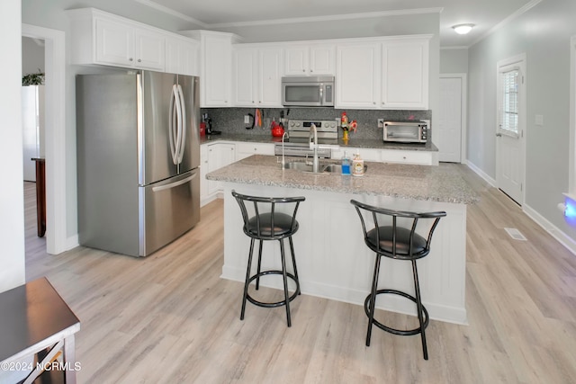 kitchen featuring an island with sink, appliances with stainless steel finishes, and white cabinets