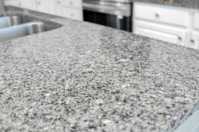 interior details featuring range, sink, and white cabinets