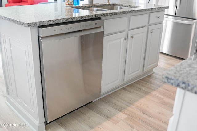 kitchen featuring sink, white cabinetry, light hardwood / wood-style floors, stainless steel appliances, and a kitchen island with sink