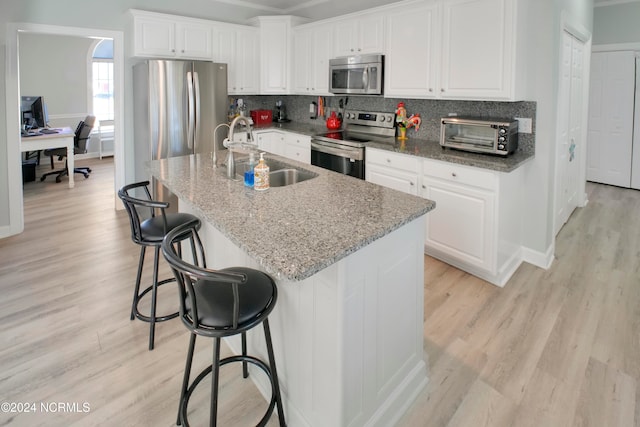 kitchen with white cabinetry, appliances with stainless steel finishes, sink, and a center island with sink