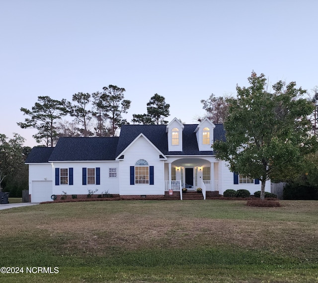 cape cod-style house with a front lawn, covered porch, and a garage