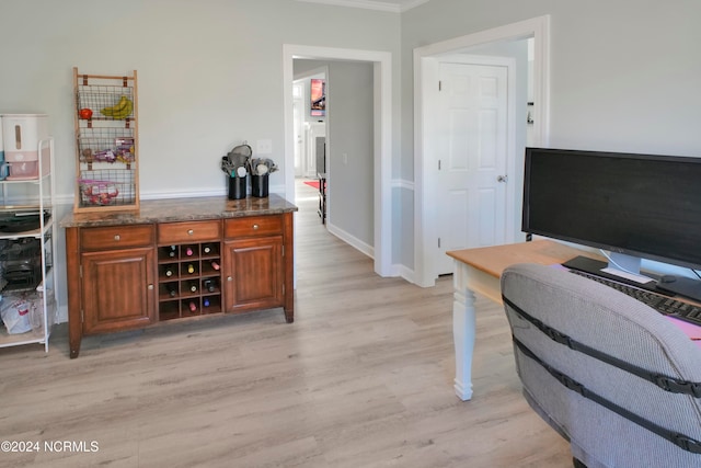 bar with dark stone countertops and light hardwood / wood-style floors