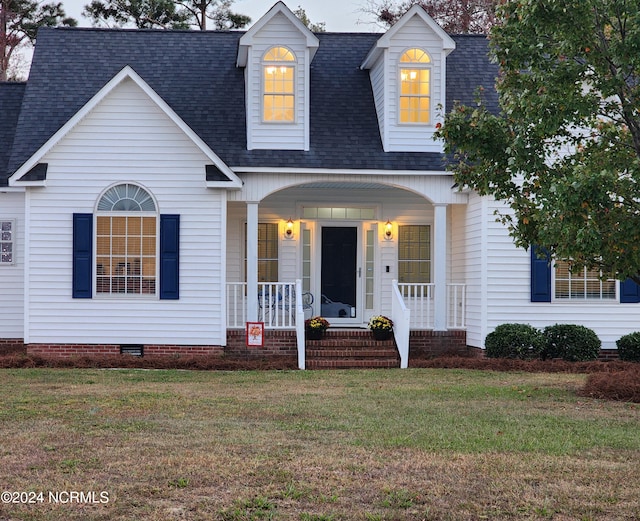 cape cod home featuring a front lawn and covered porch