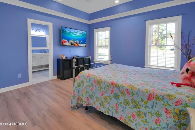 bedroom with ensuite bath and light wood-type flooring