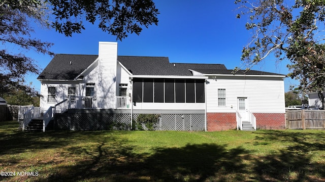 rear view of property featuring a wooden deck, a sunroom, and a yard