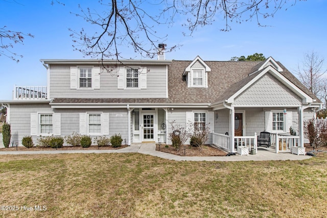 view of front of house with roof with shingles, a chimney, a porch, and a front yard