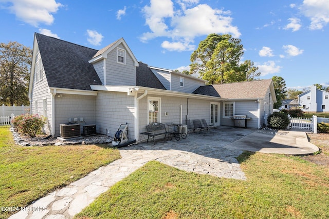 back of house featuring roof with shingles, fence, a lawn, and a patio