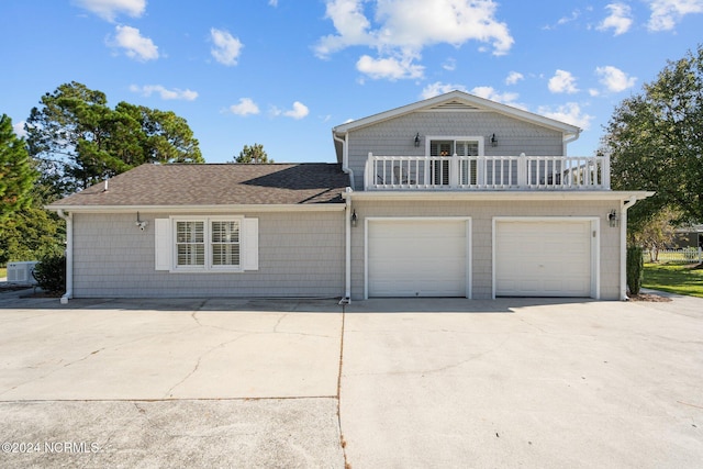 view of front of house with a garage, concrete driveway, a shingled roof, and a balcony