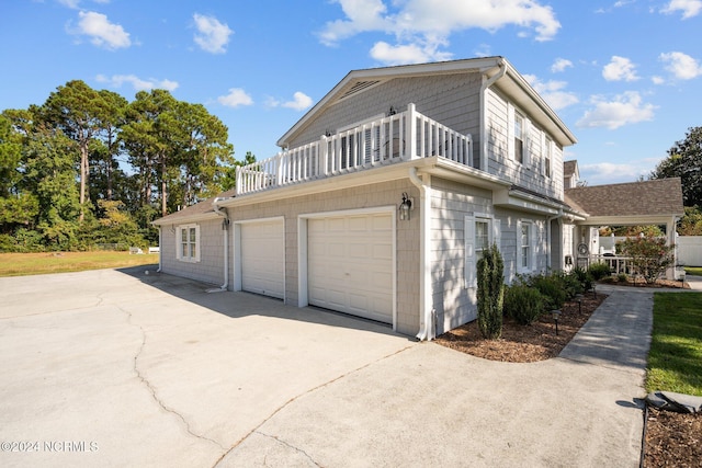 view of side of home with a garage, driveway, and a balcony