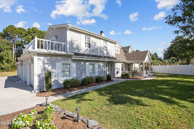 rear view of property with a balcony, a garage, and a lawn