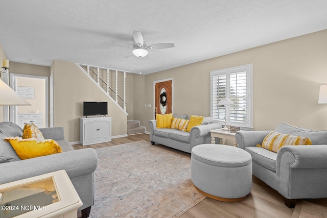 living room featuring a textured ceiling, wood-type flooring, and ceiling fan