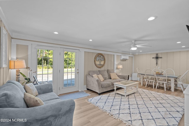 living room featuring light hardwood / wood-style floors, ornamental molding, a wall mounted AC, and ceiling fan