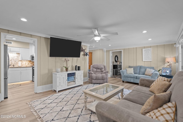 living room with ornamental molding, wooden walls, light hardwood / wood-style flooring, and ceiling fan