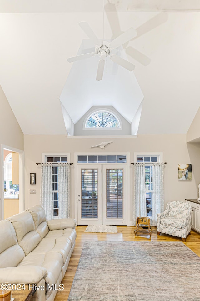 living room featuring ceiling fan, high vaulted ceiling, and light hardwood / wood-style flooring