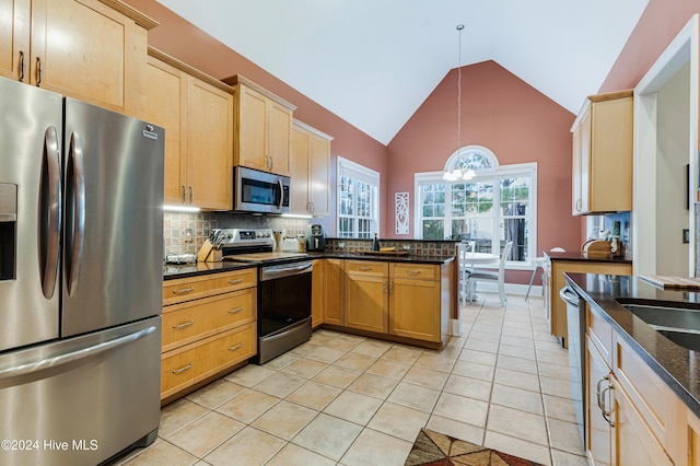 kitchen featuring high vaulted ceiling, hanging light fixtures, dark stone countertops, appliances with stainless steel finishes, and light tile patterned flooring