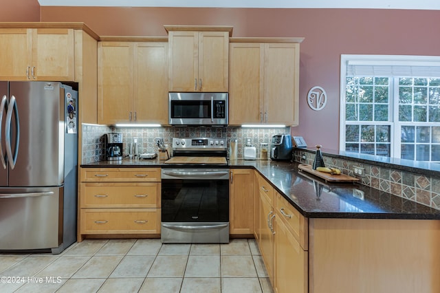 kitchen featuring backsplash, light tile patterned floors, dark stone counters, and appliances with stainless steel finishes