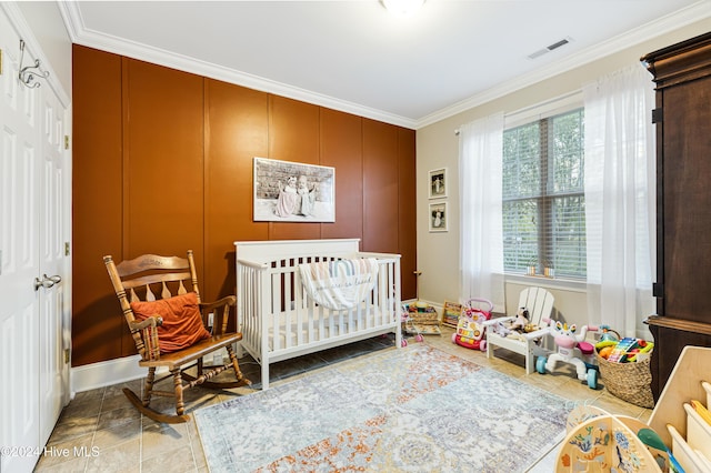 bedroom featuring light tile patterned flooring, a crib, and crown molding