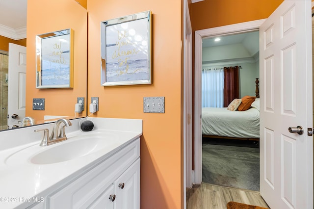 bathroom featuring wood-type flooring, vanity, lofted ceiling, and crown molding