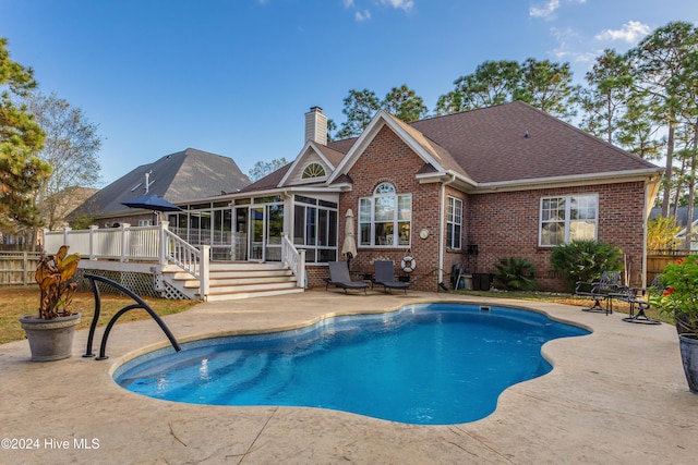 view of pool with a patio, a deck, and a sunroom