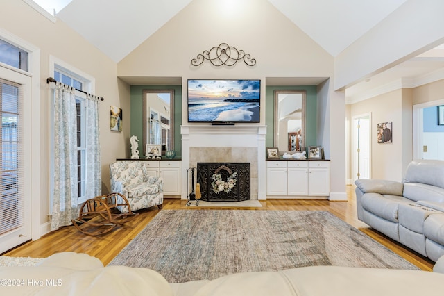 living room with a tiled fireplace, high vaulted ceiling, and light hardwood / wood-style floors