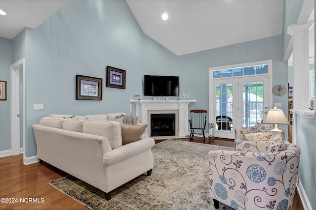 living room with hardwood / wood-style floors, french doors, high vaulted ceiling, and decorative columns