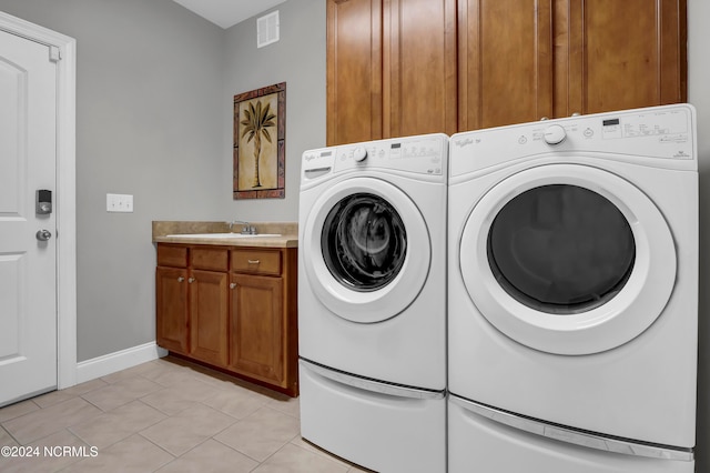 laundry area featuring sink, washer and clothes dryer, light tile patterned floors, and cabinets