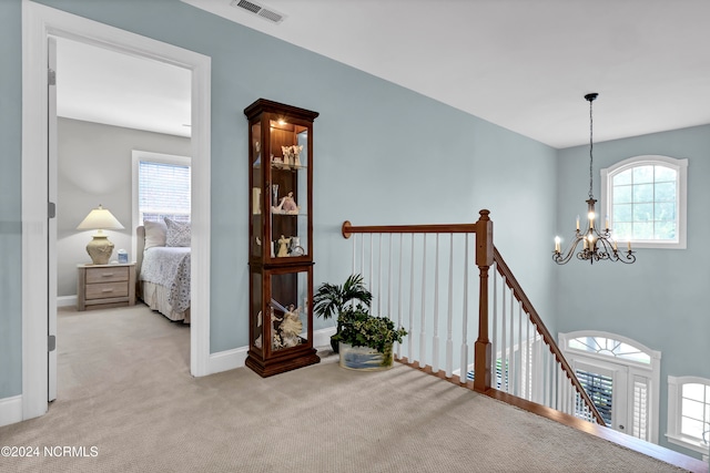 hall featuring a chandelier, light colored carpet, and plenty of natural light