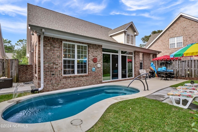 rear view of house featuring a fenced in pool and a patio