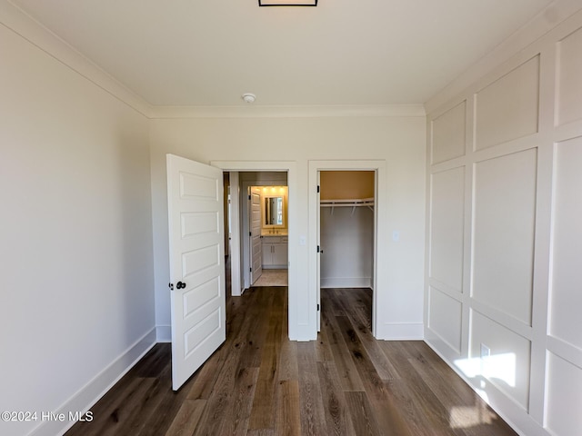 unfurnished bedroom featuring dark hardwood / wood-style floors, a walk in closet, crown molding, and a closet