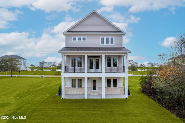 exterior space with a patio, a balcony, brick siding, french doors, and a front yard