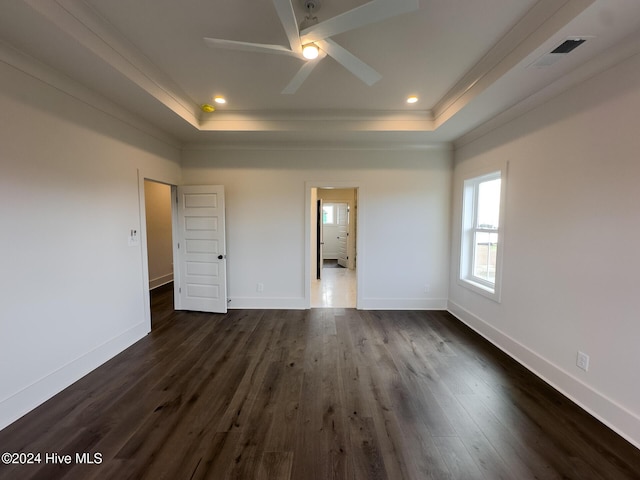 unfurnished bedroom featuring a tray ceiling, dark hardwood / wood-style floors, crown molding, and ceiling fan