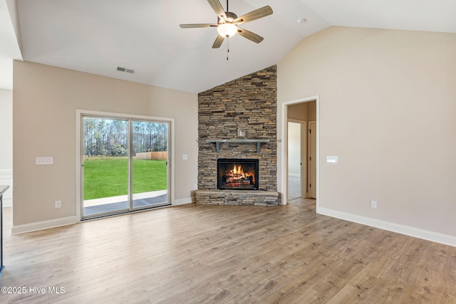 unfurnished living room featuring visible vents, ceiling fan, a stone fireplace, wood finished floors, and high vaulted ceiling