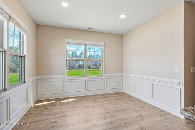 unfurnished room with light wood finished floors, visible vents, and a healthy amount of sunlight