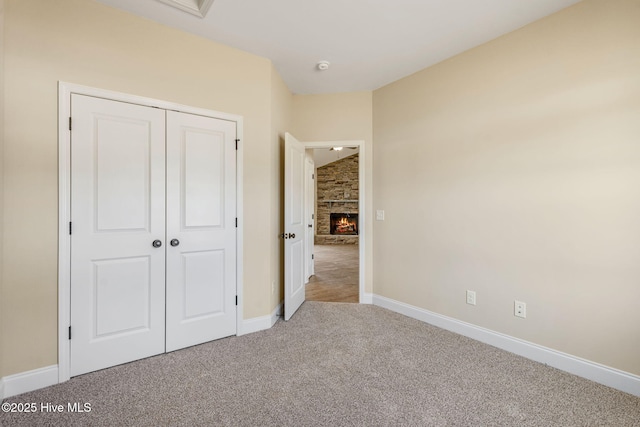 unfurnished bedroom featuring a closet, carpet flooring, a fireplace, and baseboards