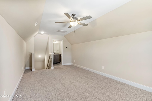 additional living space featuring baseboards, visible vents, a ceiling fan, light colored carpet, and lofted ceiling