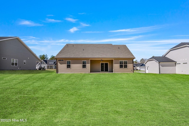 back of property with a shingled roof and a lawn